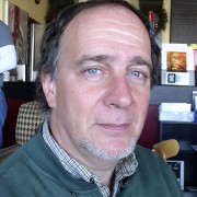 Serious-looking man with receding dark hair and gray facial hair